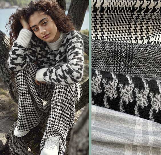 Seated girl dressed in small houndstooth pant & larger houndstooth jumper with white sneakers.