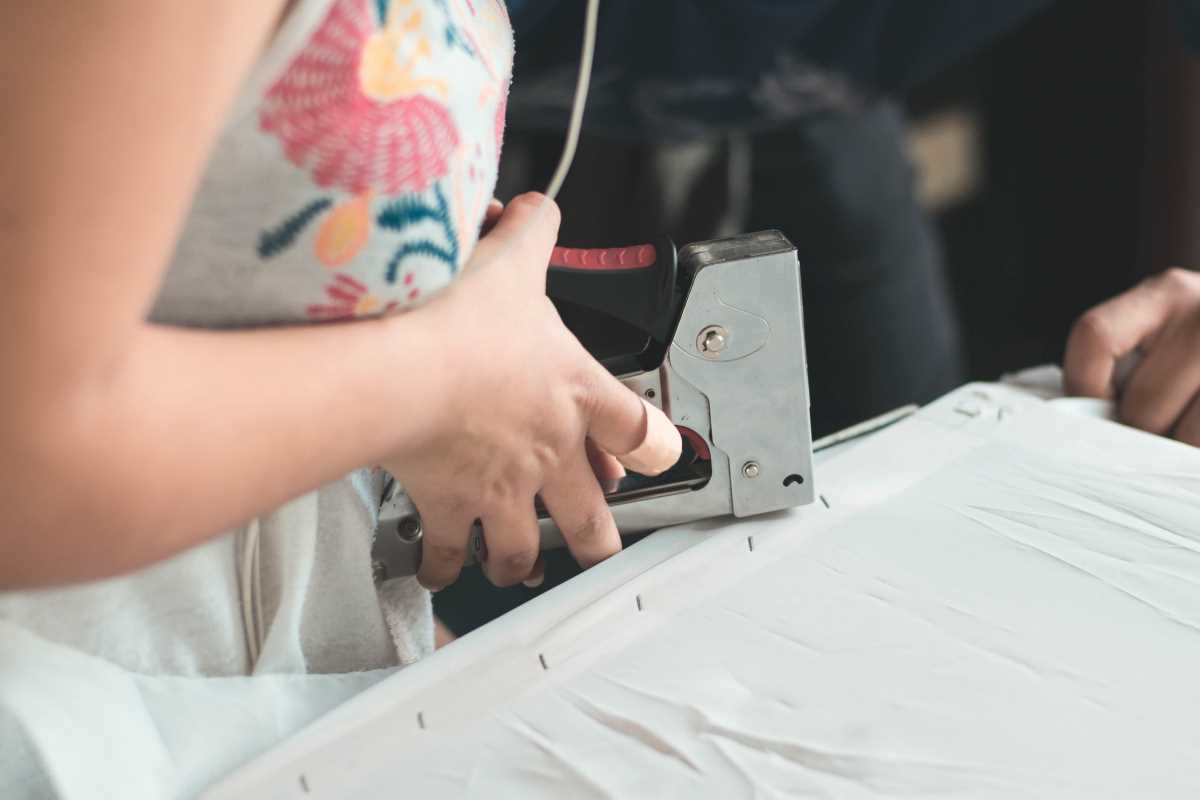 A lady using a staple gun to secure fabric to a frame in a craft project