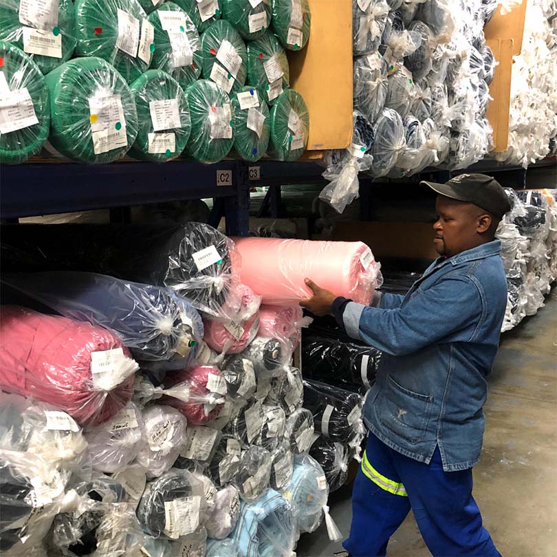 An employee selecting a pink roll of fabric from the warehouse storage stock