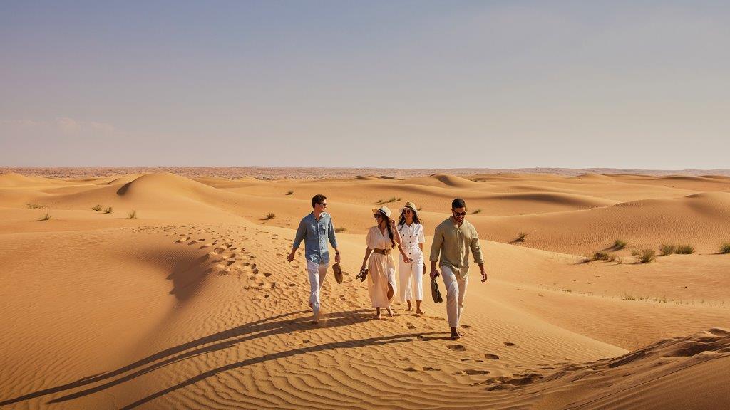 Desert scene with 4 people taking a stroll in linen outfits.